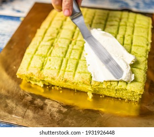 Spreading swiss meringue buttercream on a freshly baked pandan cake. - Shutterstock ID 1931926448