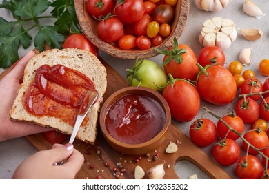 Spreading Tomato Sauce On Toasted Bread,female Hands Smear Tomato Sauce Spread On Sandwich Bread. Preparing Lunch Or Breakfast. Tomato Sauce With Garlic And Vibrant Green Leaves Of The Italian Parsley