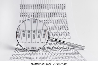 Spreadsheet with magnifying glass. Statistic data analysis and audit. Business and finance concept. Income, expenses calculation. High quality photo