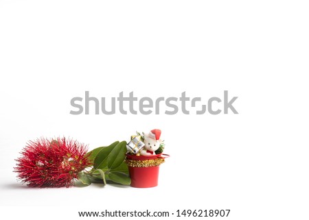A sprig of red flowering pohutukawa (New Zealand Christmas tree) with Christmas decorations on a white background.
