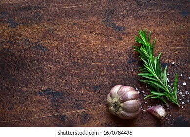 Sprig of rosemary with garlic and sea salt - traditional italian spices on a dark rustic wooden background. Top view with copy space. - Powered by Shutterstock