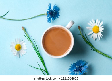 Spring Background. Cornflowers, Chamomile And A Cup Of Hot Coffee On A Blue Background. Top View 