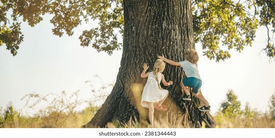 Spring banner. Happy children on countryside. Climbing trees children. Little boy and girl climbing high tree. Funny brother and sister. - Powered by Shutterstock