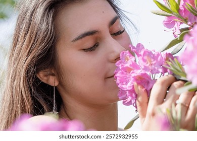 Spring blossom. beautiful young woman wearing white summer dress surrounded by pink rhododendron blossom