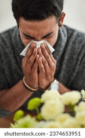 Spring, blowing nose with a man using a tissue closeup in his home for relief from allergy symptoms. Face, cold or flu and a young person sick with a virus due to pollen or hay fever at home