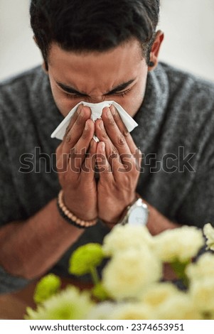 Spring, blowing nose with a man using a tissue closeup in his home for relief from allergy symptoms. Face, cold or flu and a young person sick with a virus due to pollen or hay fever at home