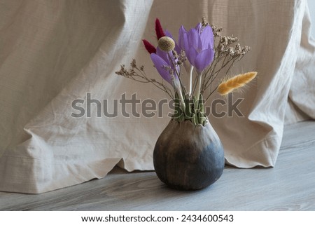 Spring bouquet of first flowers crocuses in handmade ceramic vase on beige textile curtain. interior design and minimalist decor