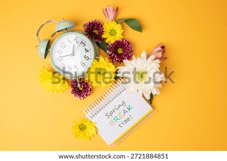 Spring break time text, message on lined note pad with alarm clock and fresh flowers.
