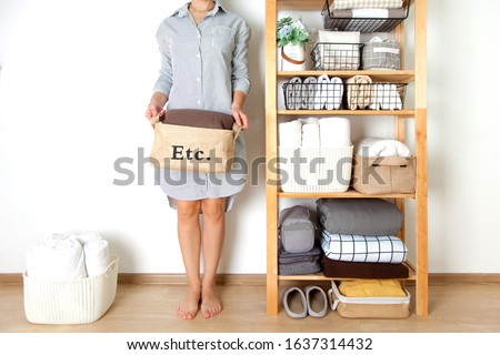 Spring cleaning of closet. Vertical tidying up storage. Neatly folded bed sheets in the metal black baskets for wardrobe. Nordic style.