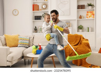 Spring cleaning. Father and daughter singing while tidying up together at home - Shutterstock ID 2325478395