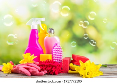 Spring Cleaning Office Or House Concept. Different Cleaning Supplies Over Blurred Spring Background Among Floating Soap Bubbles. Copy Space