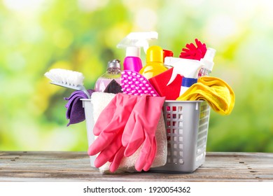 Spring Cleaning Office Or House Concept. Different Cleaning Supplies In A Basket Over Blurred Spring Background Among Floating Soap Bubbles. Copy Space