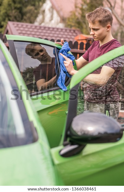 Spring\
cleaning. Young boy is polishing the green\
car.