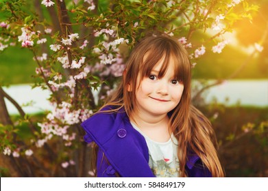 Spring close up portrait of 4-5 year old kid girl wearing purple jacket
