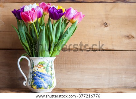 spring colorful tulips in vase and wooden background, free space