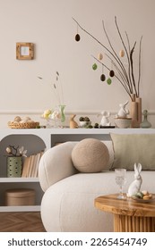 Spring composition of easter living room interior with mock up poster frame,  modern sideboard, coffee table easter eggs, round pillow, easter bunny and personal accessories. Home decor. Template.