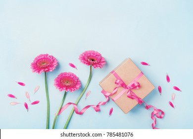 Spring Composition With Pink Flowers And Gift Box On Blue Table Top View. Greeting Card For Birthday, Woman Or Mothers Day. Flat Lay.