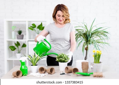 Spring Concept - Portrait Of Mature Woman Watering Potted Plants At Home