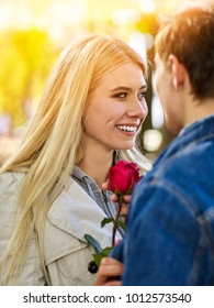 Spring Couple Walking Park. Summer Friends Walk Sun Shine. First Date Of Two Young People In Good Weather Day. Guy Gives Girl Red Rose Flower. Girl Laughs Gaily With Her Head Thrown Back. Toning Of