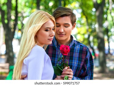 Spring Couple Walking Park. Summer Friends Walk Sun Shine. First Date Of Two Young People In Good Weather Day. Guy Gives Girl Flower.