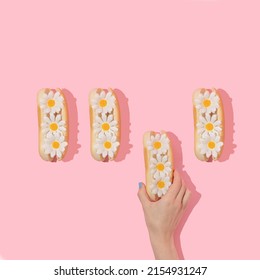 Spring creative layout with hand taking white flowers in hot dog buns pastel pink background. 80s or 90s retro fashion aesthetic bloom concept. Minimal romantic food idea. - Powered by Shutterstock