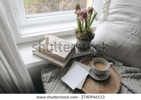 Spring Easter Window Still Life with Coffee Cup, Pink Hyacinth Flowers, Books and Blank Greeting Card Mockup. Elegant Home Interior Still life Scene, Soft Natural Light, Copy Space. Flat lay. Top view