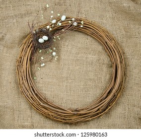 A spring or Easter wreath crafted from a nest, eggs, willow and twigs on a burlap background with room for text