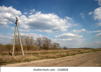 Spring fields, road, electric line and the blue sky with clouds