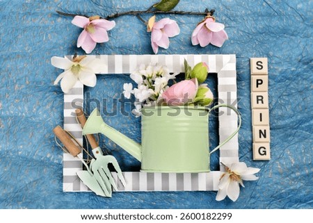 Spring flat lay background with watering can, flowers and gardening tools inside photo frame