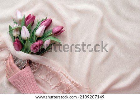 Spring flat lay with female hands holding bunch of tulips on cream, beige textile background. Springtime holiday card design with copy-space. Easter, Mothers day, March 8 International Women's day.