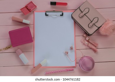spring flat lay in rose tone. empty notebook and lipstick, headphone,rose glasses, earrings, handbag on a pink wooden  background. flat lay with fashion accessories in pastel pink tones.Top view