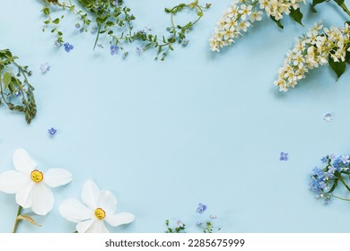 Spring flowers flat lay on blue background. Floral card template with space for text. Happy easter! Mothers day! Daffodils, forget me nots and wildflowers in frame layout