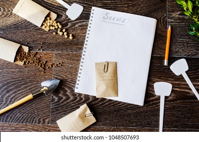 Spring Garden Preparation For Sowing Vegetable Seeds And Planning. Pumpkin, Coriander With Labels, Peat Pots And Tools On Note Book. Seasonal Garden Work.