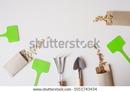 spring garden work flat lay with vegetable seeds in handmade envelopes, labels, peat pots and garden tools on wooden table. Seasonal work and preparations