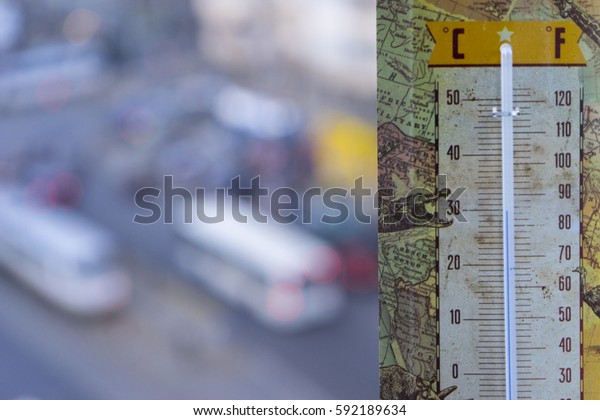 Spring is\
here/Thermometer showing around 25 degrees celsius in the\
foreground and in focus with the street traffic in the defocused\
background on the first day of\
spring.