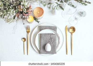 Spring holiday table set up. Easter table decor with linen napkins eggs and golden cutlery.  - Powered by Shutterstock