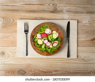 Spring Homemade Radish Salad With Fresh Cucumber And Greens On Wooden Plate Top View. Simple Green Rustic Salat With Sliced Radishes, Cucumbers, Escarole And Lettuce