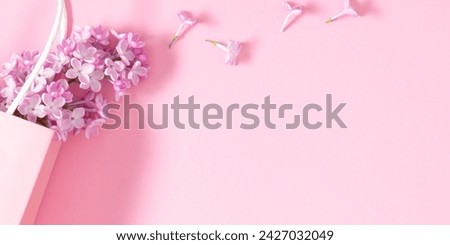 Spring  lilac flowers. Gift bag and lilac branches on pink background. Flat lay, top view, copy space