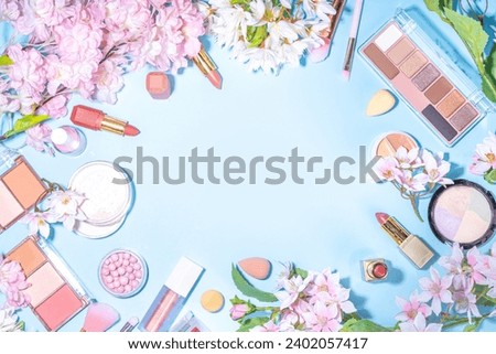 Spring make up set on light blue background. Different make-up professional cosmetics, beauty accessories flat lay with spring blossom flowers top view copy space