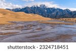 Spring at Medano Creek - A bright sunny Spring morning view of Medano Creek rushing down a sandy valley at base of rolling Great Sand Dunes and snow-capped Mt. Herard. Great Sand Dunes National Park.