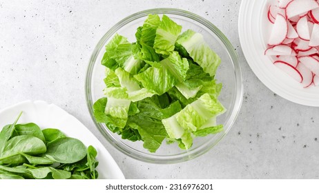 Spring mix salad in a glass bowl. Romaine lettuce, baby spinach, and fresh radish slices close-up on the kitchen table, flat lay with copy space - Powered by Shutterstock