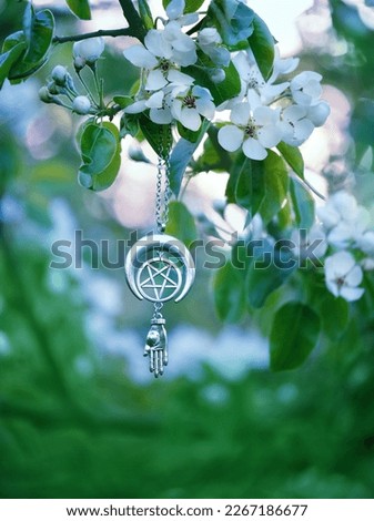 spring nature background. amulet with pentacle on blossoming tree, abstract green background. pagan witch ritual, spiritual wiccan practice. esoteric symbol of pentagram and hand