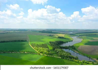 Spring nature in Ukraine. Green fields and meadows, white clouds and blue sky. River among the fields. Electric pillars in the middle of the field. Top view drone shot of a green field and river.  - Powered by Shutterstock