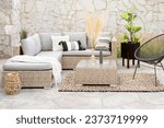 Spring Patio Furniture Set with Rattan Sectional Sofa, Decorative Pillow Covers, Wicker Patio Chairs, and Rattan Coffee Table, on a Botanical Area Rug in an Outdoor Living Space, Decorative Stone Wall