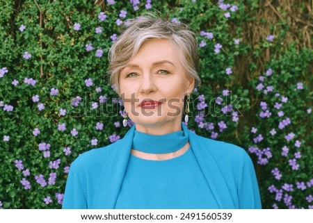 Spring portrait of beautiful mature 55 - 60 year old woman posing outside