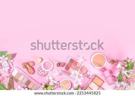 Spring professional makeup flat lay. Spring make up set on pink background. Different make-up cosmetics, beauty accessories flat lay with spring blossom flowers top view copy space 