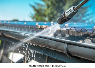 Spring Rain Gutters Cleaning Using Pressure Washer. Closeup Photo.