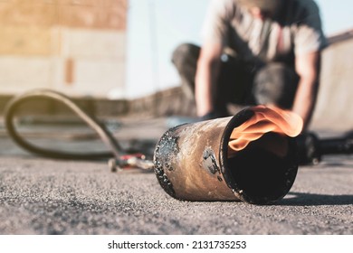 spring repair of a soft roof with rolled materials using a gas burner, the front and background are blurred with a bokeh effect - Powered by Shutterstock