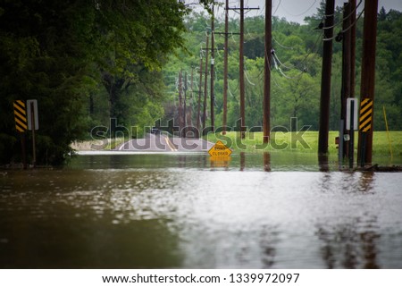 Spring river flooding of rural farmland featuring flooded fields, water over road and farm under water