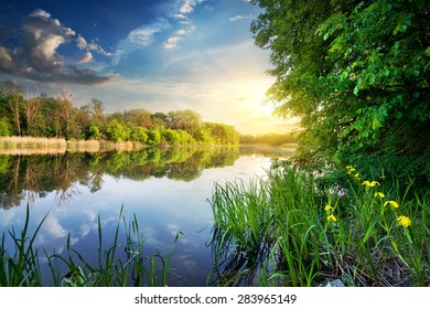 Spring river and green forest at sunset